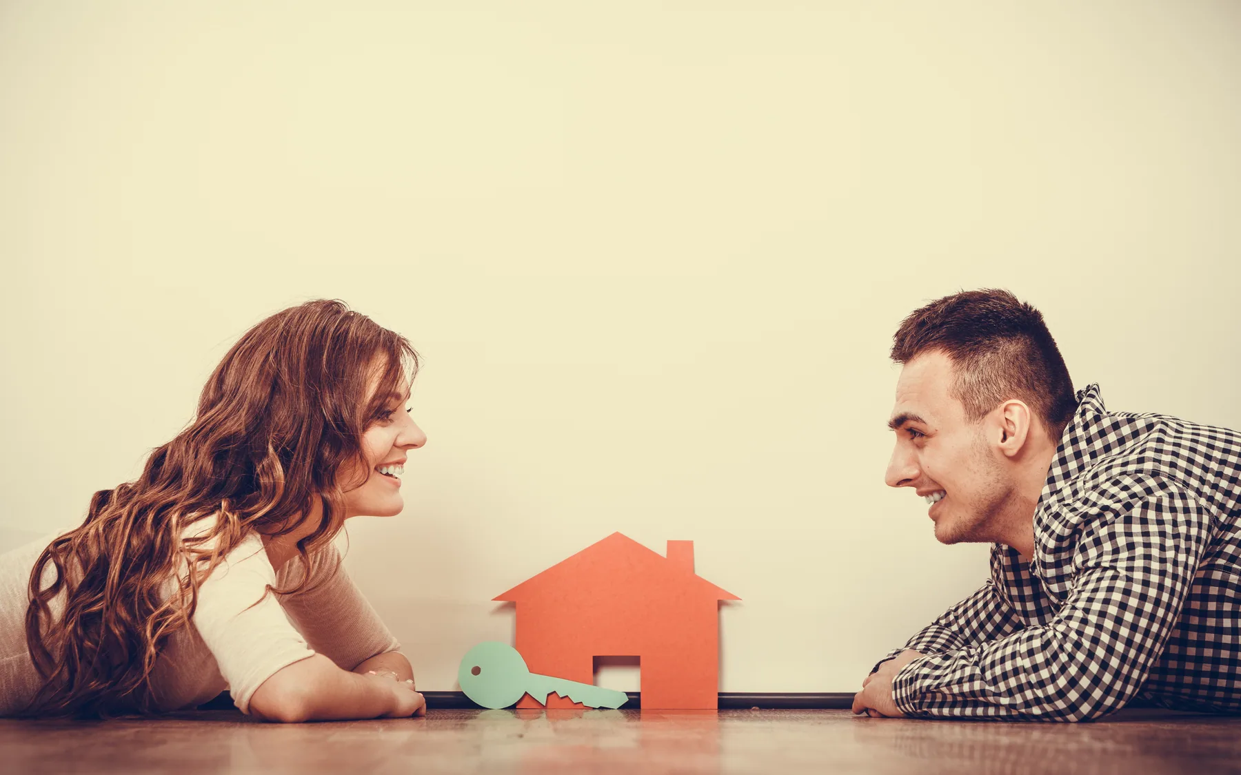 Una pareja conversa frente a una pequeña casa de papel.